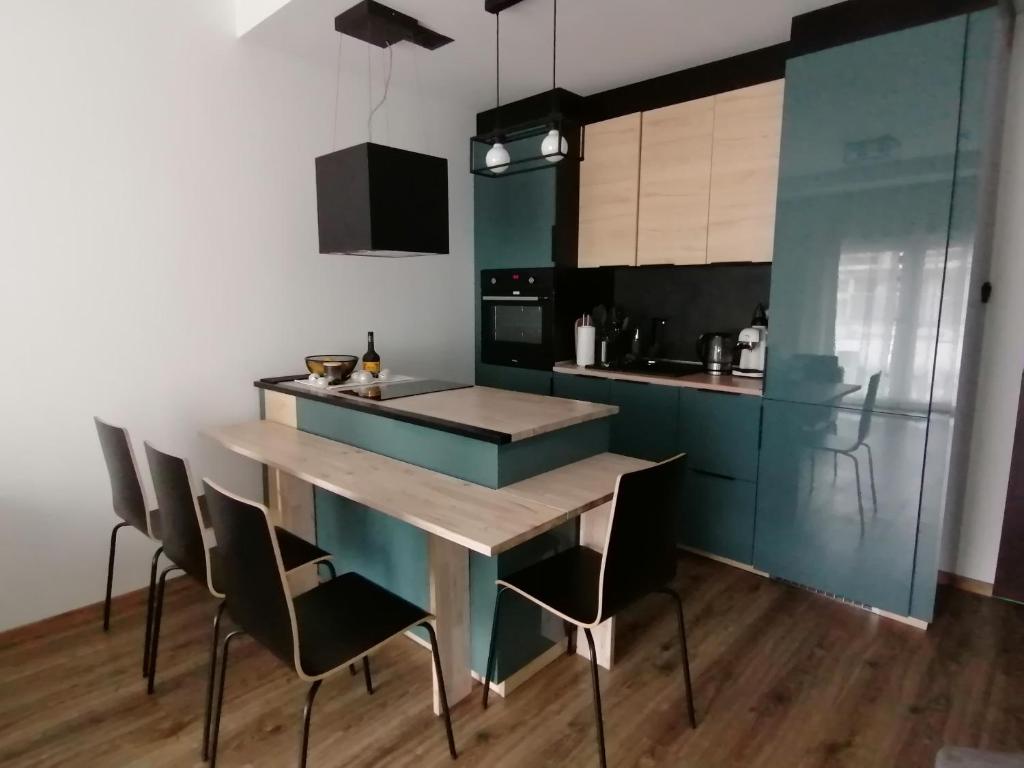 a kitchen with blue cabinets and a wooden table and chairs at Nad Zalewem 9/1 in Dziwnówek