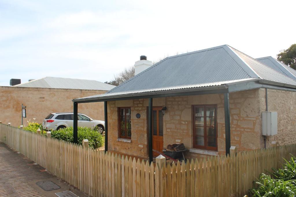 a small brick house with a wooden fence at Victoria Cottage in Robe