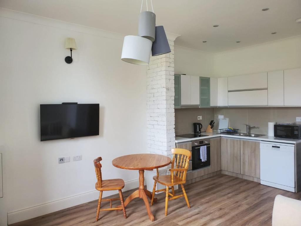 a kitchen with a wooden table and two chairs and a table at Grand Norfolk in Mundesley