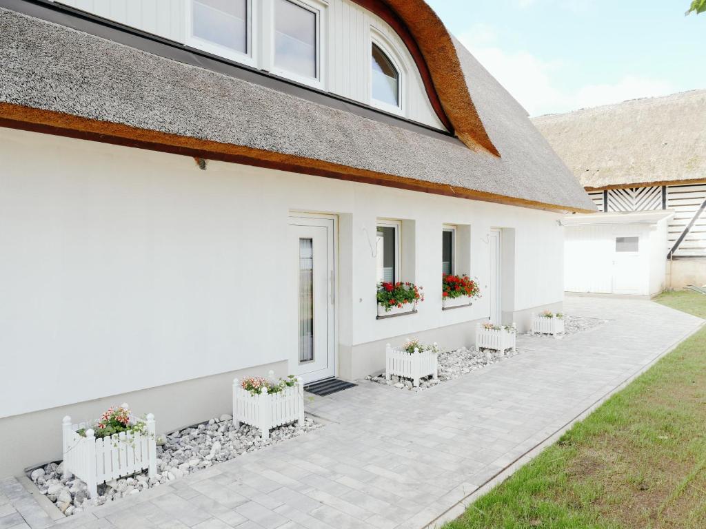 ein weißes Haus mit Topfpflanzen auf einer Terrasse in der Unterkunft Ferienwohnungen am Reiterhof Sallenthin in Neu Sallenthin