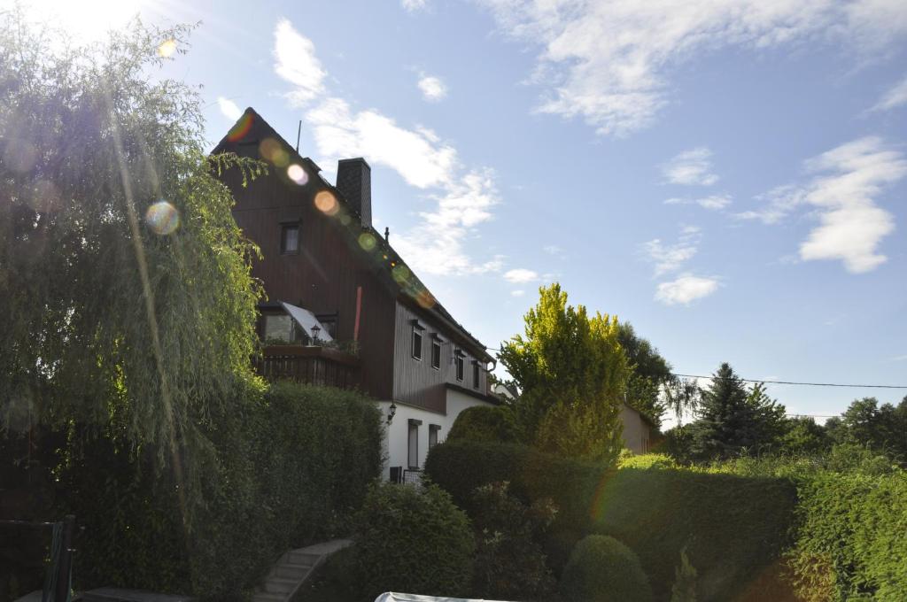 uma casa com uma cerca e arbustos à sua frente em Zum Landidyll em Lugau