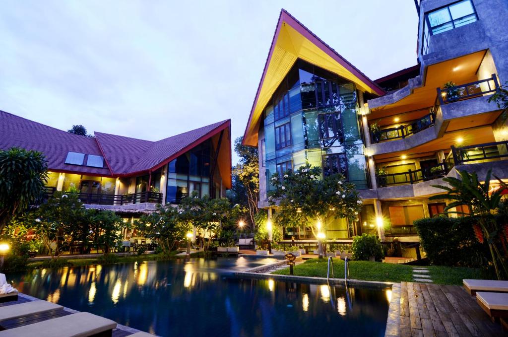 a hotel with a swimming pool in front of a building at Kireethara Boutique Resort in Chiang Mai