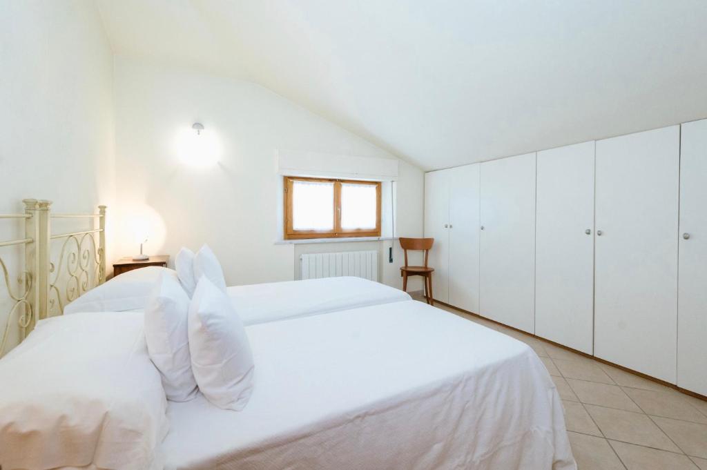 um quarto branco com 2 camas e uma janela em Casa GINESTRA a Bagno Vignoni em Bagno Vignoni