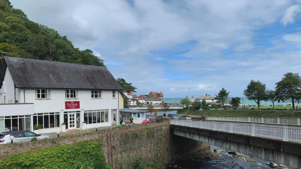 ein weißes Gebäude neben einem Fluss mit einer Brücke in der Unterkunft The Lyn Valley Guest House in Lynmouth