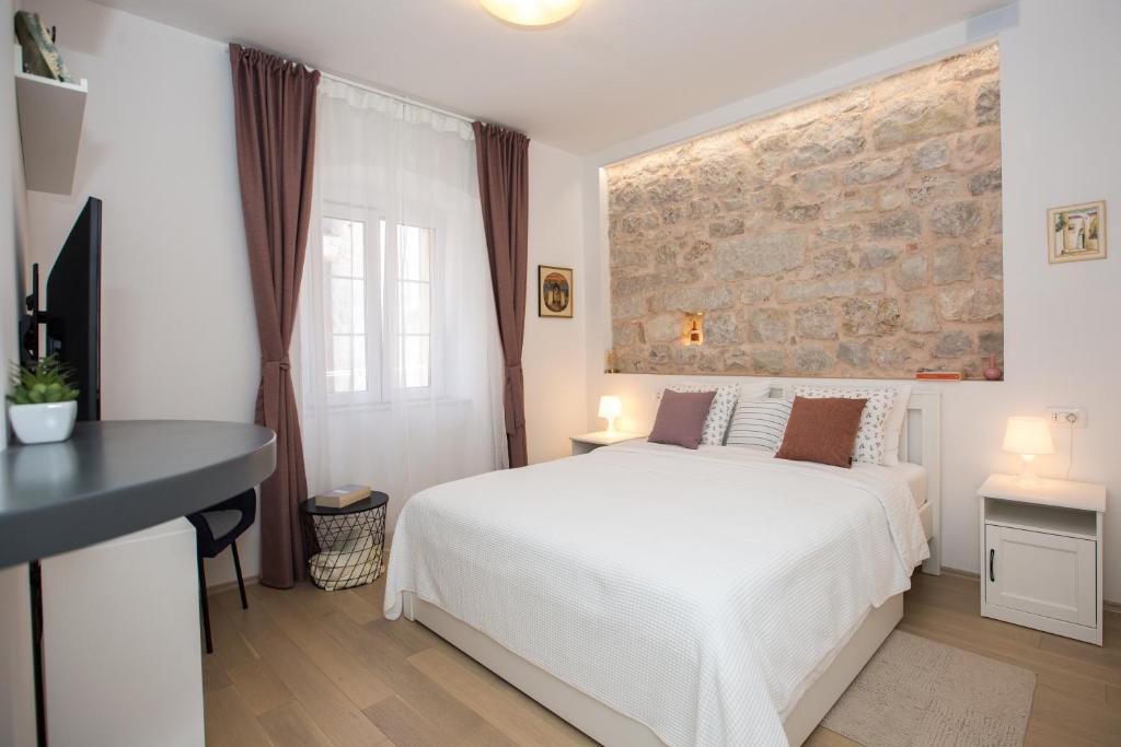 1 dormitorio con cama blanca y pared de ladrillo en Liberty Town Center Rooms en Dubrovnik
