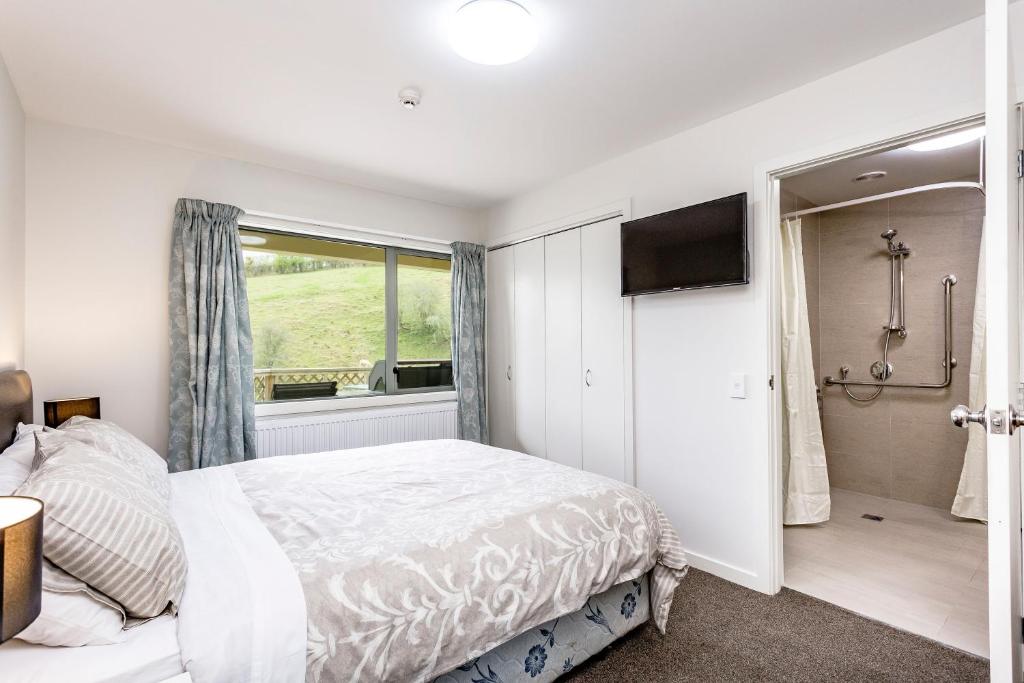 a bedroom with a bed and a shower and a television at Hunters Moon in Mosgiel