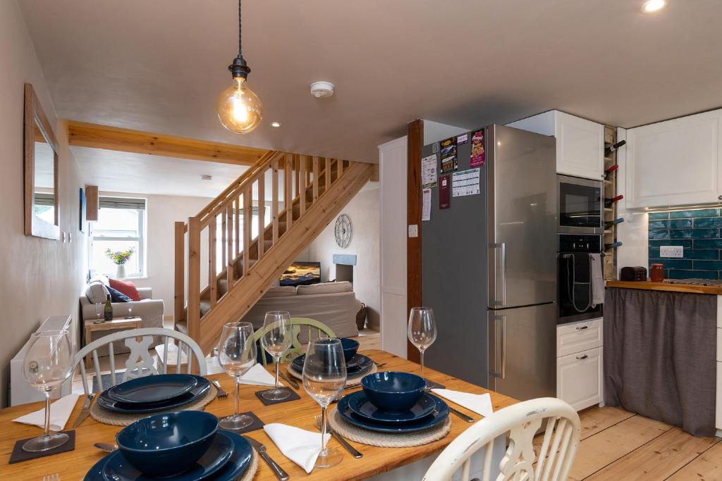 uma cozinha e sala de jantar com uma mesa com pratos e copos de vinho em Snowdon Street em Llanberis