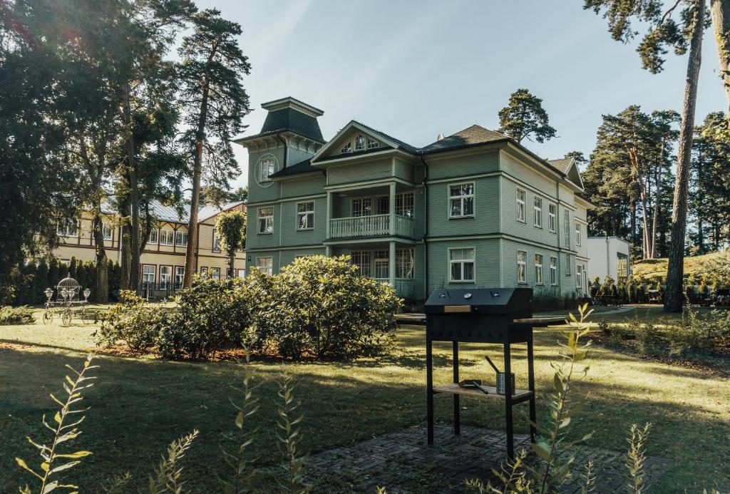 a large green house with a grill in front of it at Baltic Sea Dunes Apartments in Jūrmala