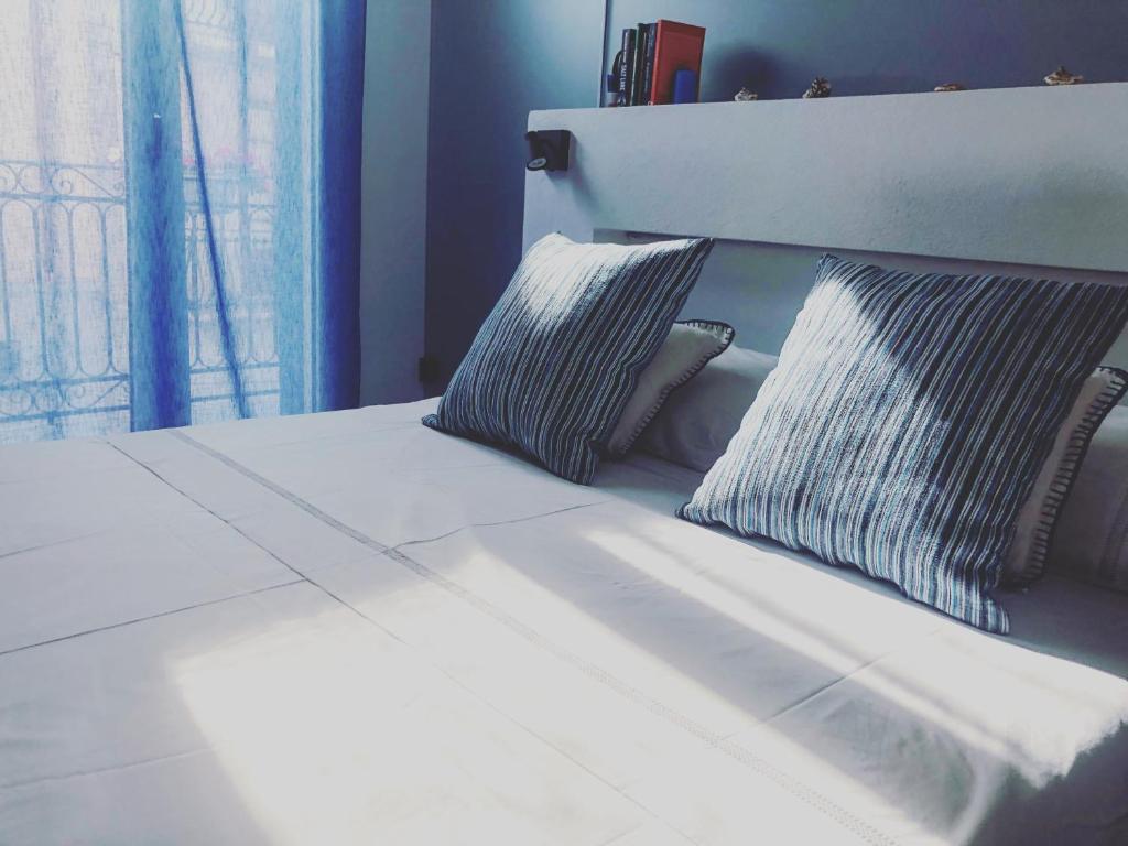 a white bed with two pillows and a window at Calida B&B in Castellammare del Golfo