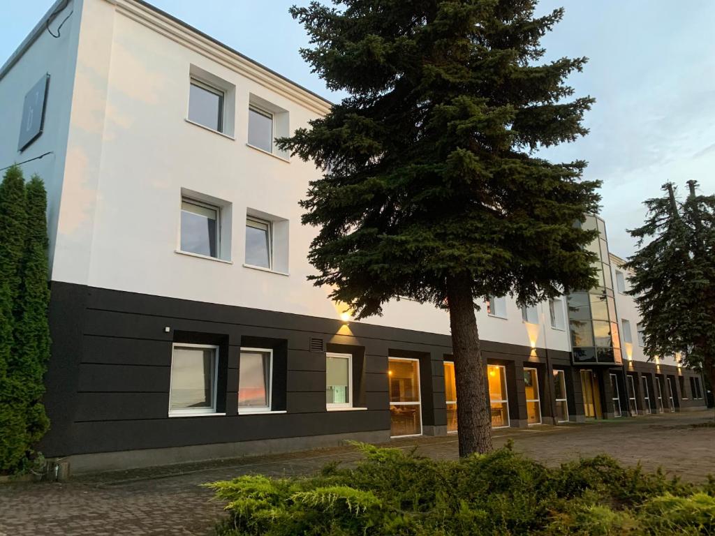un bâtiment avec un arbre en face dans l'établissement Bell's Hotel, à Konstantynów Łódzki