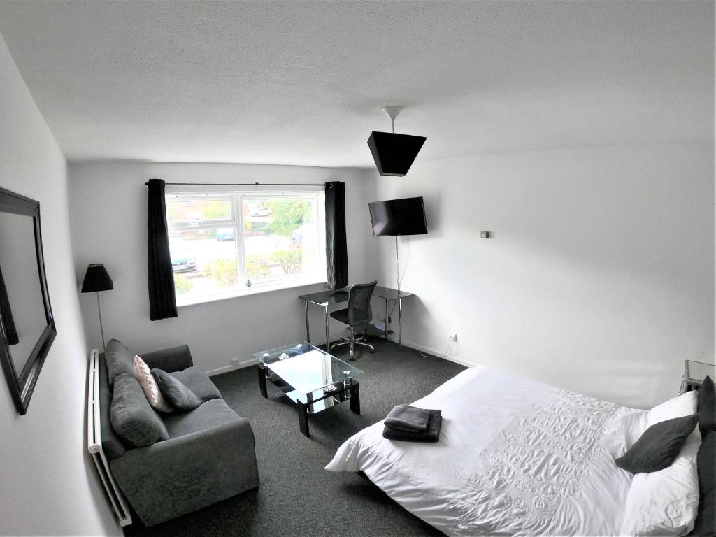 a bedroom with a bed and a chair and a window at Town Centre Studio Flat! in Basingstoke