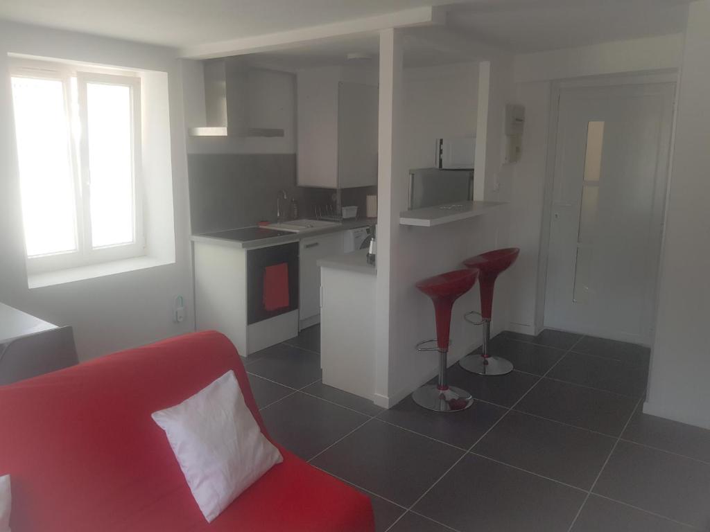 een woonkamer met een rode bank en 2 krukken bij Agréable appartement in Morbier