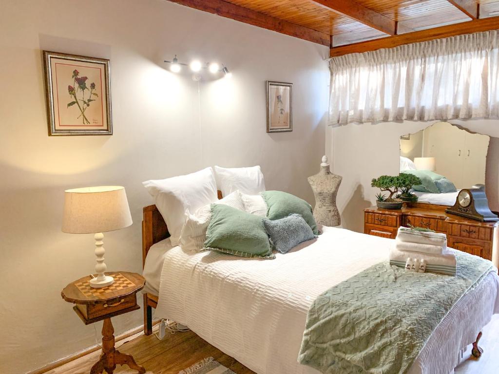 a bedroom with a large bed with green pillows at Six Second Avenue in Parys