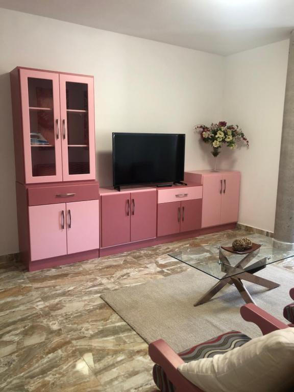 ein Wohnzimmer mit einem TV und rosa Schränken in der Unterkunft Lujan 6F entre sueños y realidad in Puntallana