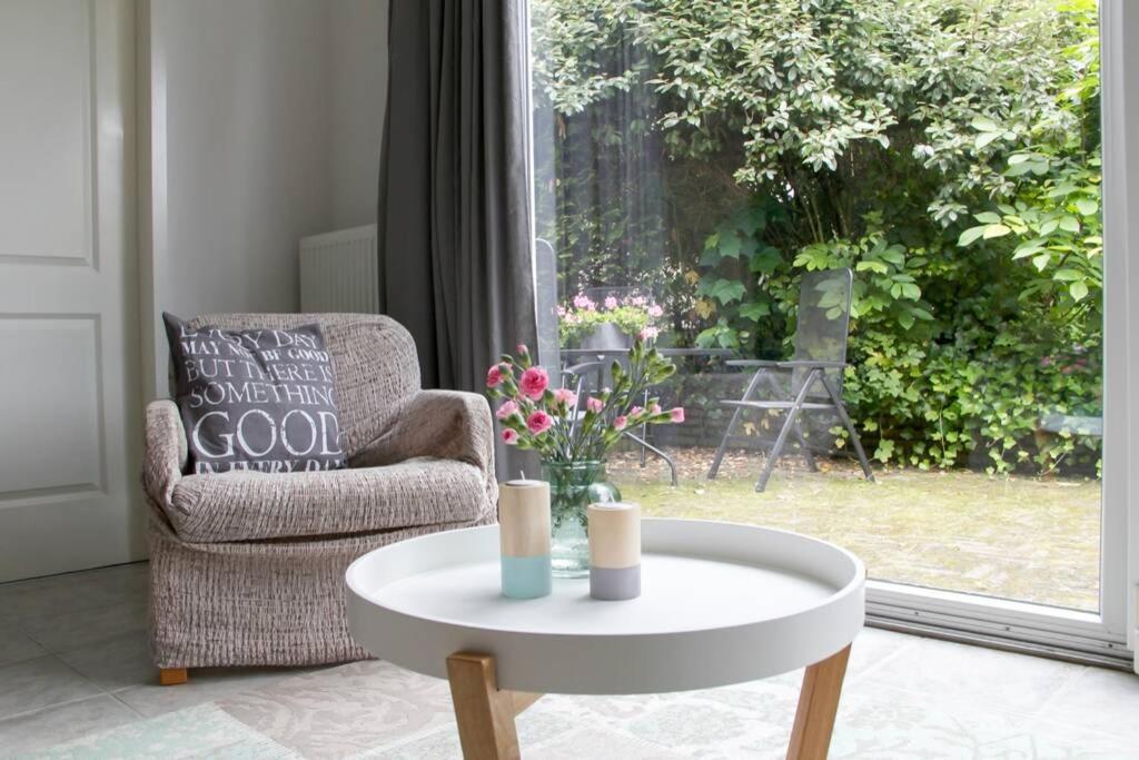 - une table basse dans le salon avec une chaise et une fenêtre dans l'établissement Knus tuin-appartement vlakbij Nijmegen voor 2 personen, à Molenhoek