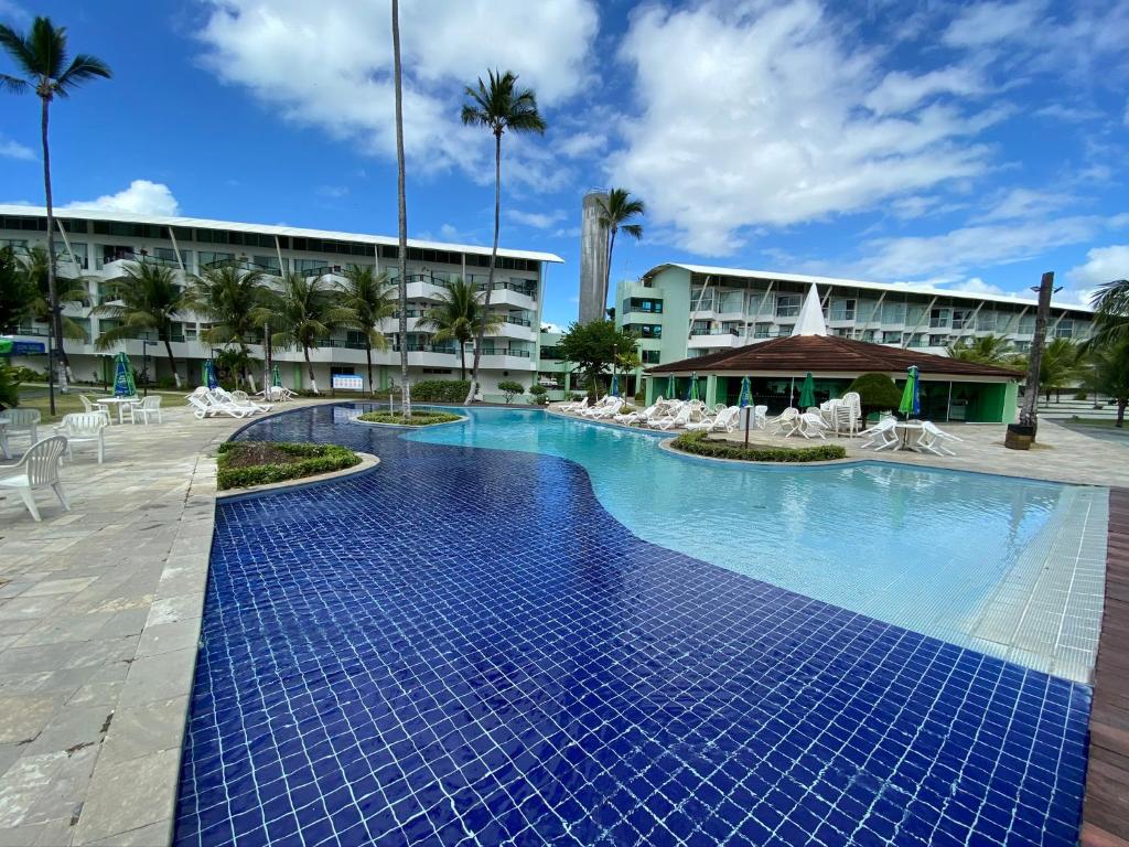 a swimming pool with blue tiles in front of a building at Ancorar Flat Resort in Porto De Galinhas