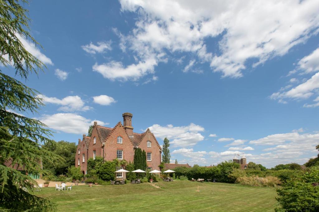 una gran casa de ladrillo en un campo de hierba en Sissinghurst Castle Farmhouse, en Sissinghurst