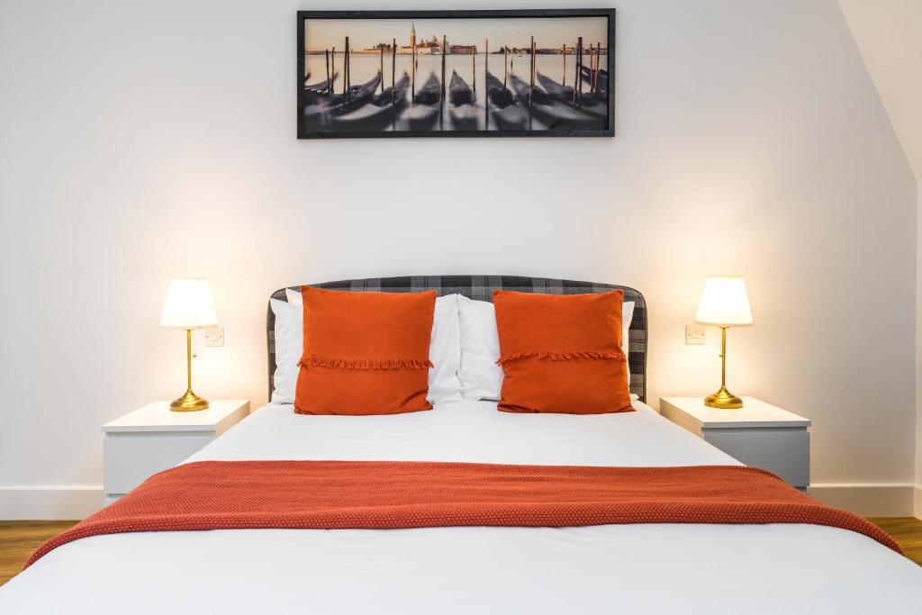 ein Schlafzimmer mit einem Bett mit orangefarbenen Kissen und zwei Lampen in der Unterkunft London City View in Woolwich