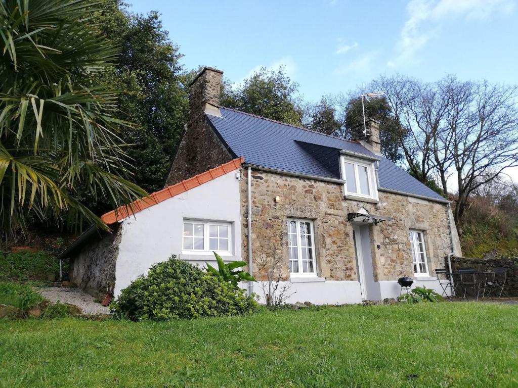 a small stone house with a black roof at Maison Normande proche de la mer et des commodités in Quettehou