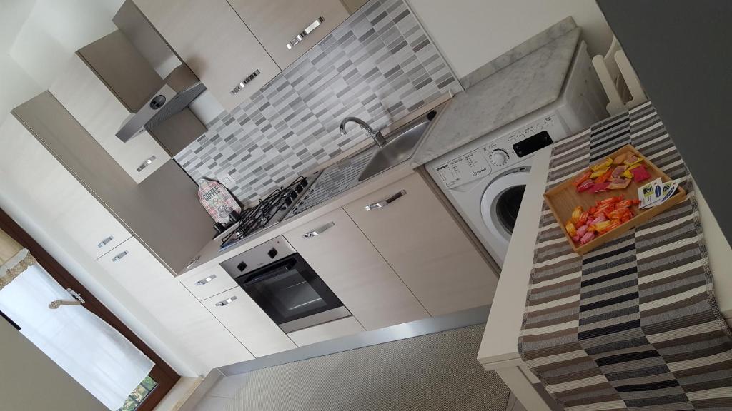 a white kitchen with a sink and a dishwasher at La casa in piazzetta in Enna