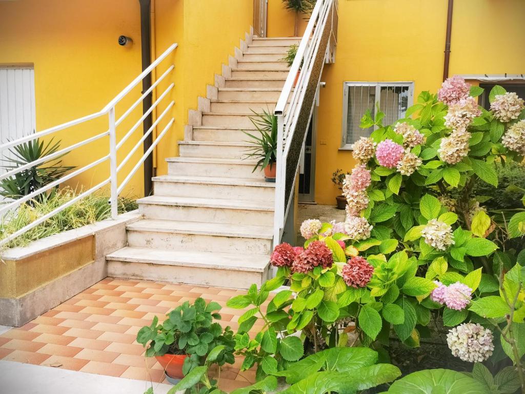 a staircase with flowers in front of a yellow building at Appartamento "C'era una volta" - Ancona in Ancona