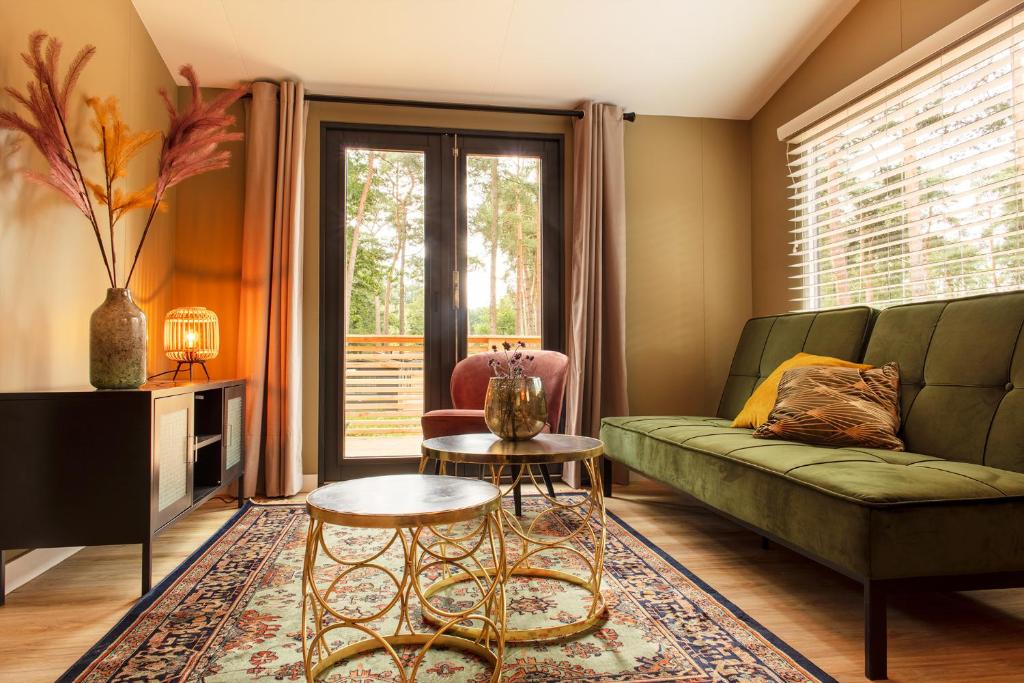 a living room with a green couch and a window at Luxe hippe Lodge in de bossen van Oisterwijk in Oisterwijk