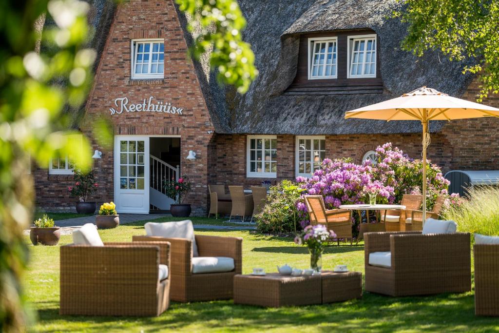 a house with a yard with couches and an umbrella at Hotel Reethüüs in Kampen