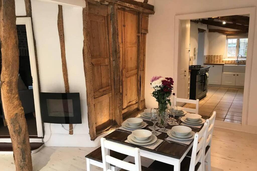 a dining room with a table with plates and flowers on it at Stunning Cottage in Picturesque Village in Radlett