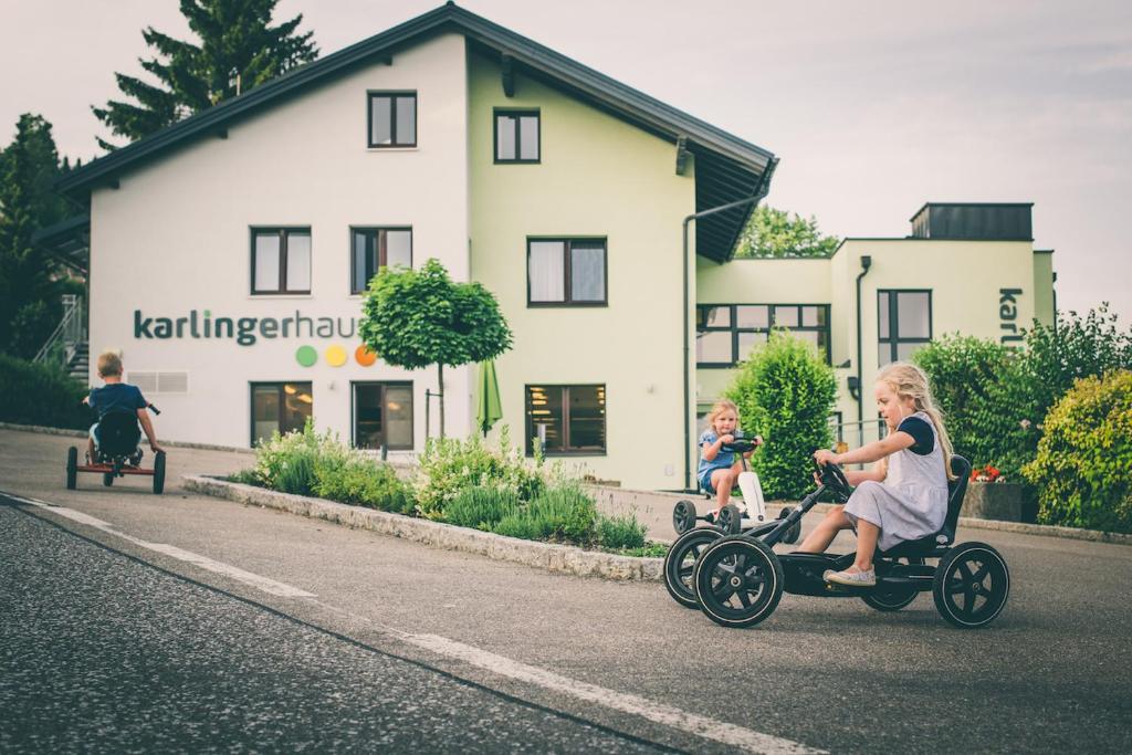 a group of children riding on toy cars down a street at Karlingerhaus in Königswiesen