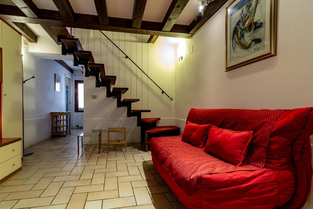 uma sala de estar com um sofá vermelho e escadas em Veneziacentopercento Gorne Apartment em Veneza