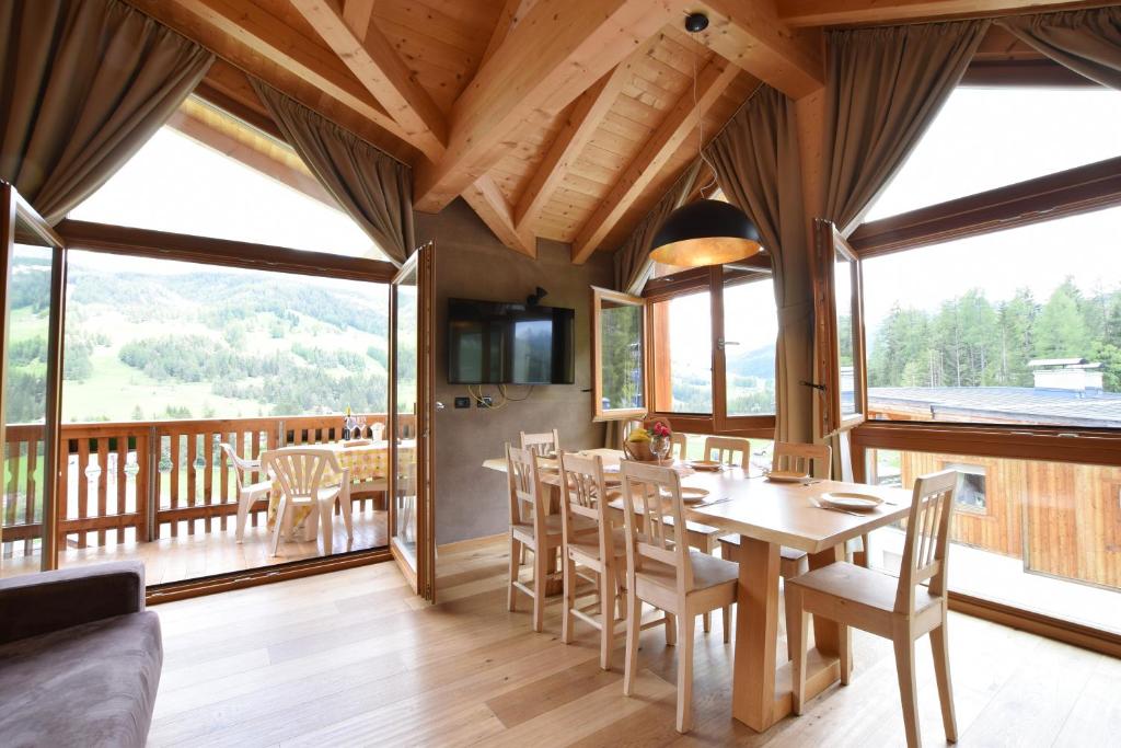 a dining room with a table and chairs and windows at Ciasa Lisüra in Badia