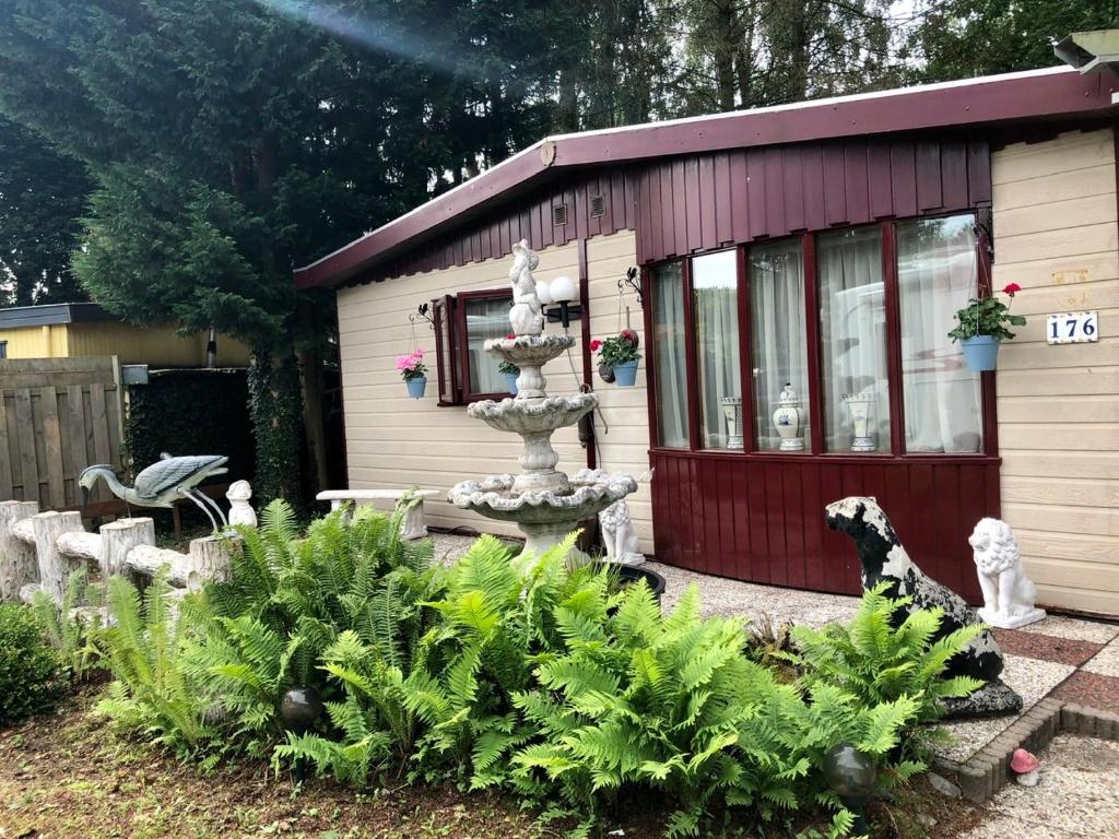 un pequeño cobertizo con una fuente en un jardín en Retro Relax Resort midden in het bos op de Veluwe in Putten, en Putten