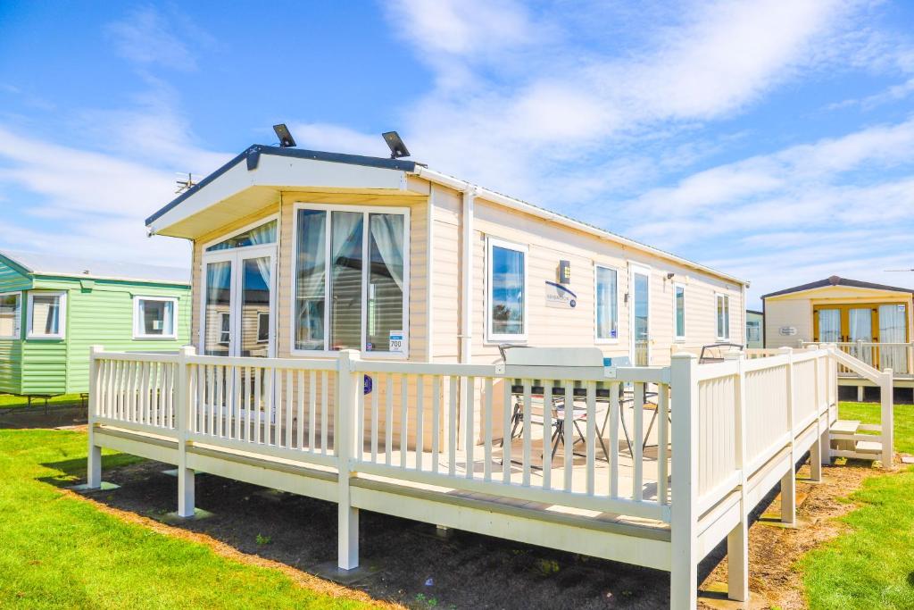 a tiny house with a porch and a deck at Big Skies Platinum Plus Holiday Home with Wifi, Netflix, Dishwasher, Decking in Camber