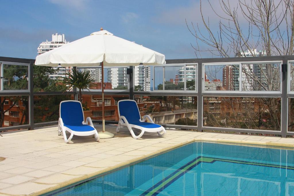 two chairs and an umbrella next to a swimming pool at Salto Grande Hotel in Punta del Este