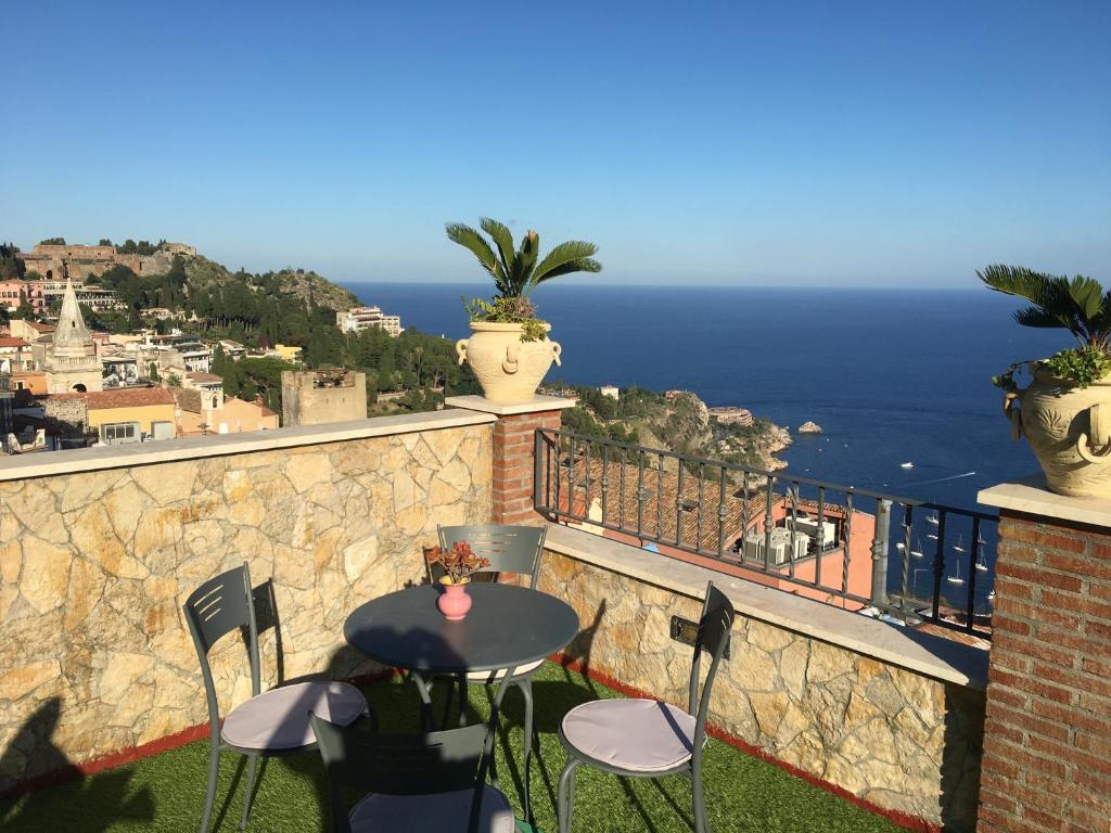 una mesa y sillas en un balcón con vistas al océano en Casa Bucalo, en Taormina