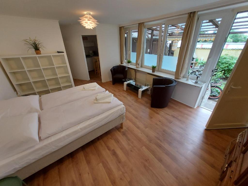 ein Schlafzimmer mit einem weißen Bett sowie Holzböden und -fenster in der Unterkunft Garden Apartment in Köln