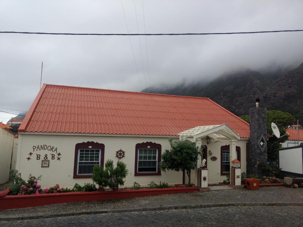 a building with a red roof in front of a mountain at Pandora in Faja Grande
