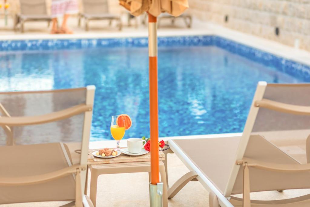 a table with a glass of orange juice next to a pool at Luxury Apartments Queen in Petrovac na Moru