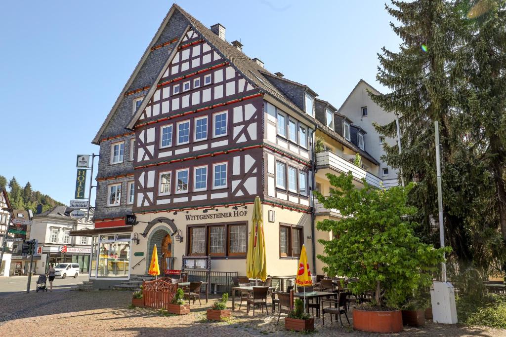 Hotel Wittgensteiner Hof في باد لاسفه: مبنى امامه طاولات ومظلات