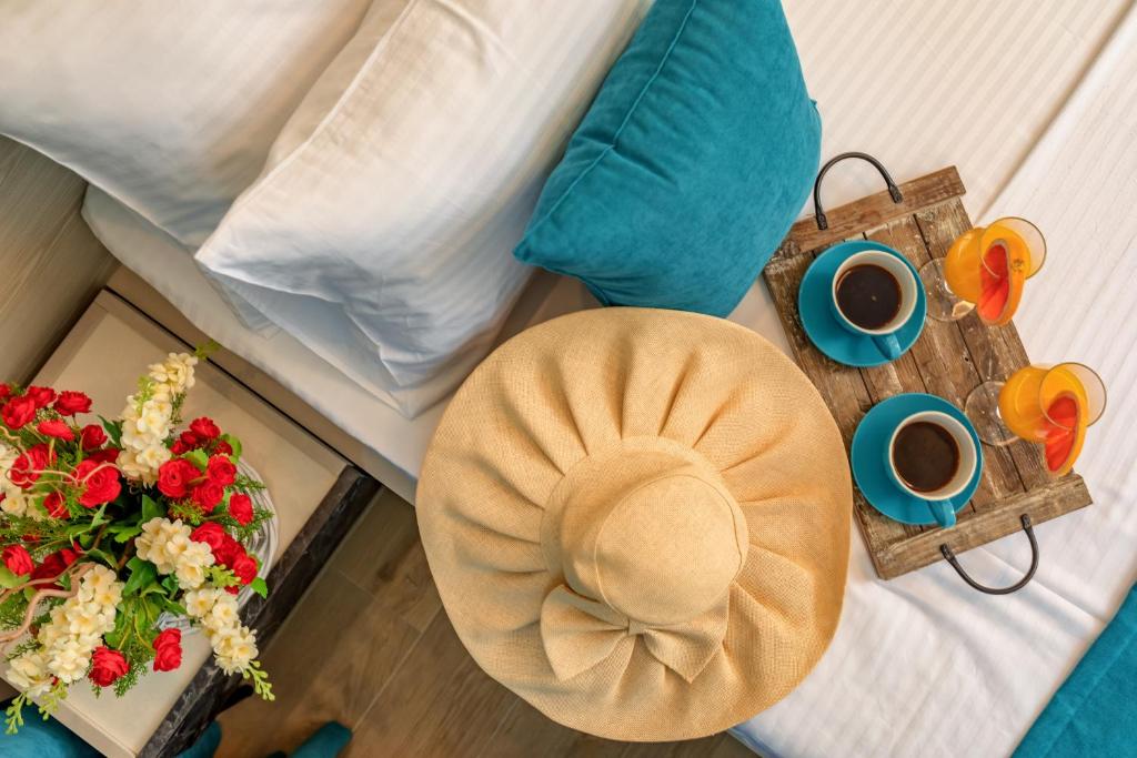 a bed with a hat and a table with coffee and flowers at Luxury Apartments Queen in Petrovac na Moru