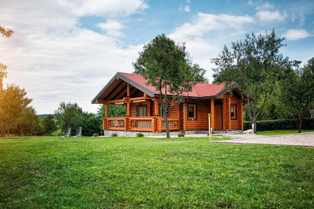 una cabaña de madera en un campo de césped verde en Country Lodge Vuković en Rakovica