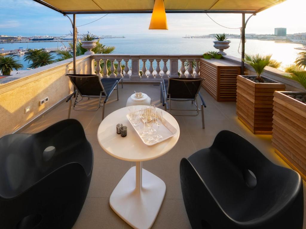 a balcony with chairs and a table and a view of the water at Riva Luxury Suites in Split
