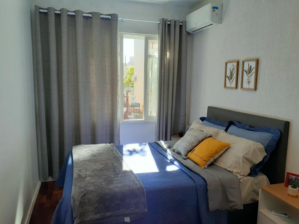 a bedroom with a bed with blue sheets and a window at Amplo, aconchegante e pertinho de tudo in Porto Alegre