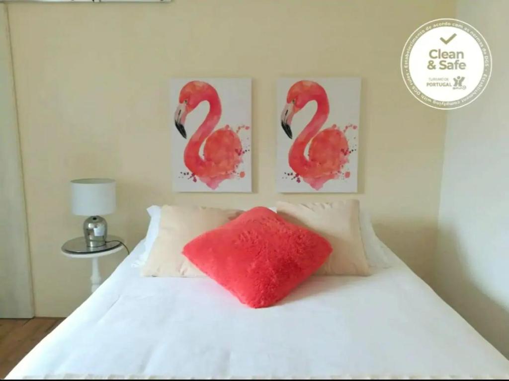 uma cama com uma almofada vermelha e duas pinturas de flamingos em BLISS WHITE HOUSE em Sintra