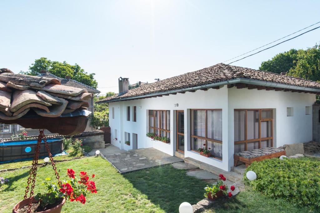 een klein wit huis met een tuin bij Къща за гости Роден край in Elena