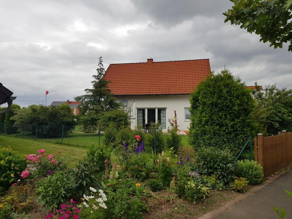 a white house with a red roof and a garden at Ferienwohnung Ina in Michelau