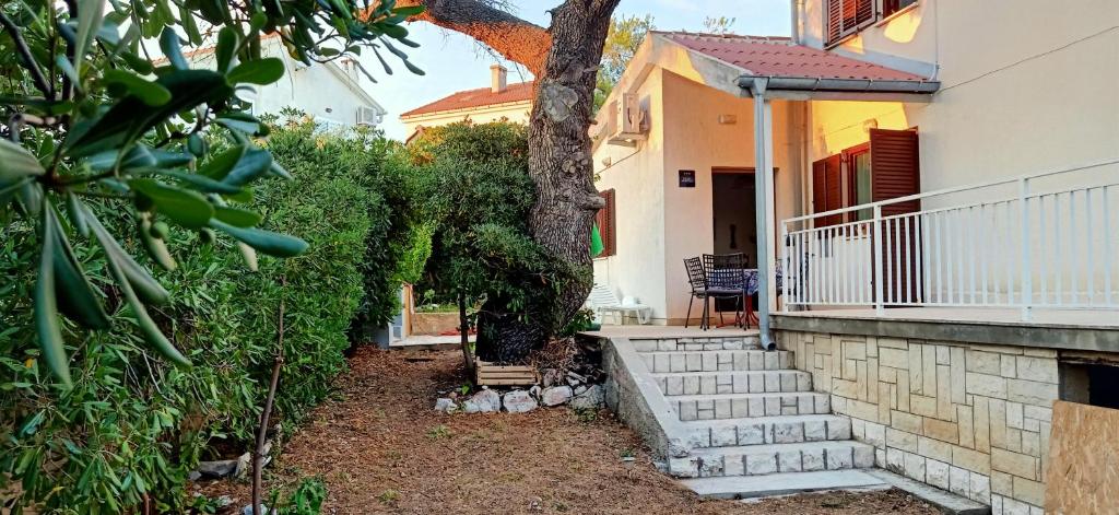 a house with stairs and a tree in front of it at Apartment Rino, only 30m to the sea in Pag