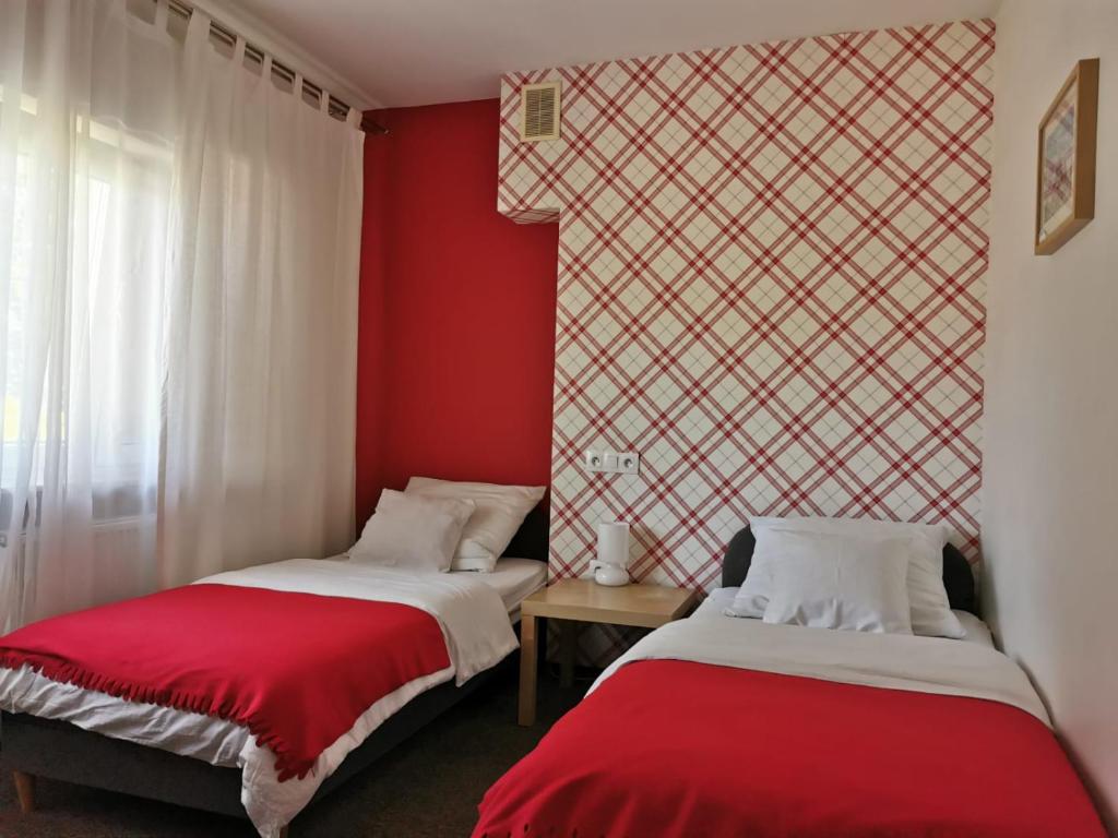 two beds in a room with red walls at Leśna Villa in Wiśniówka Mała