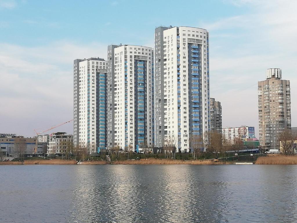 un grupo de edificios altos junto a un cuerpo de agua en ObolonSky, en Kiev