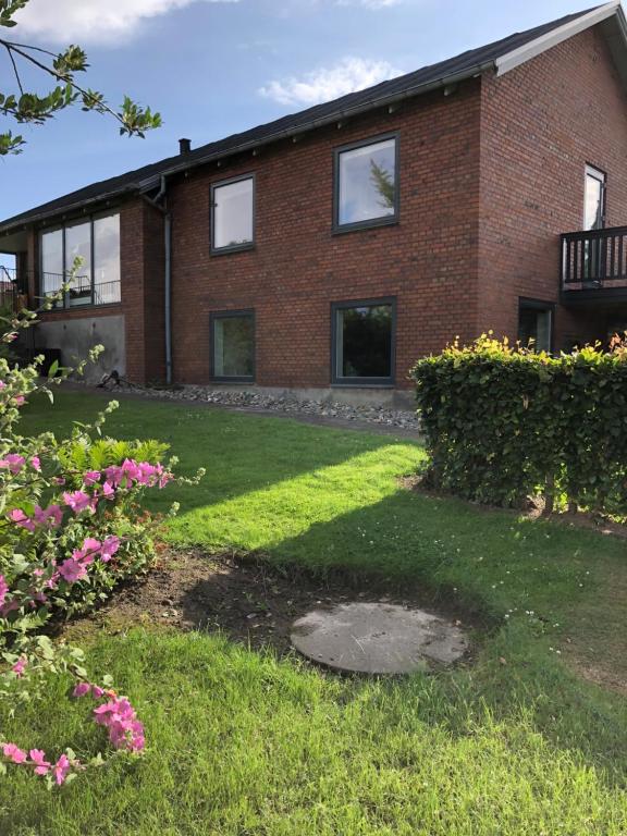 a brick house with pink flowers in the yard at Guesthouse Dybbøl, Sønderborg in Sønderborg